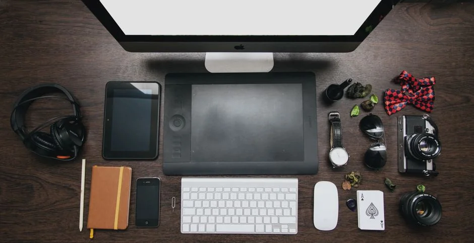 A sleek office desk setup featuring Apple devices: iMac, MacBook, and iPad.